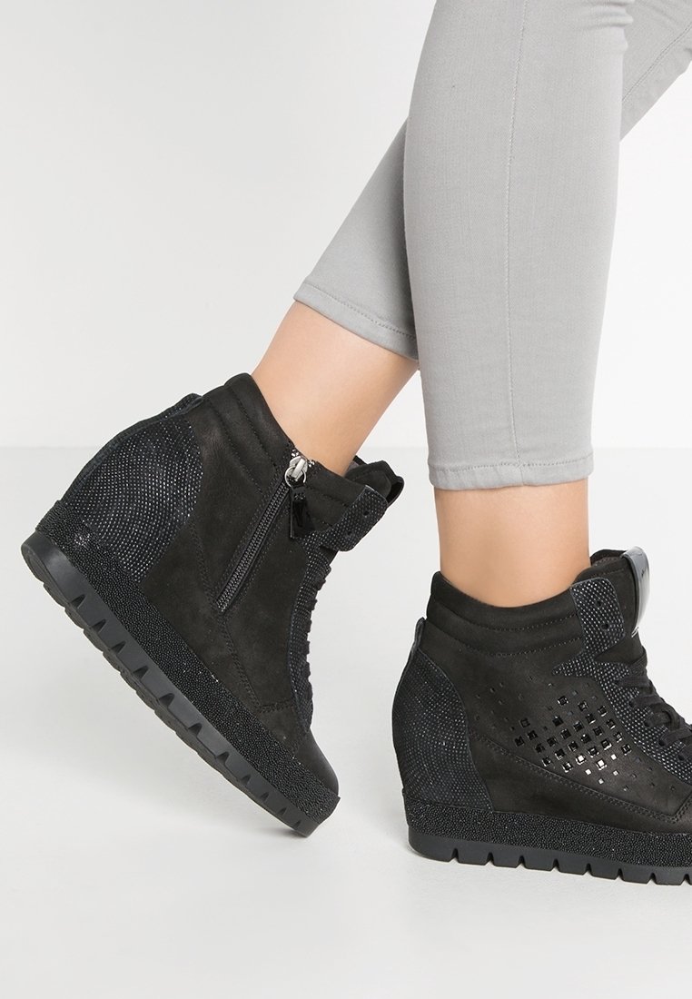 Baskets compensées noires en daim et mesh, dotées d'une fermeture éclair métallique, d'accents perforés et d'une semelle en caoutchouc texturée.
