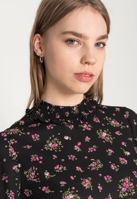 Vestido preto com padrão floral, apresentando um decote franzido, adornado com padrões em rosa e verde. Tecido suave com detalhes delicados em todo o vestido.