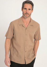 Chemise à manches courtes, col classique en tissu beige clair. Dotée de cinq boutons et d'une texture subtile, avec un logo brodé sur la poitrine.