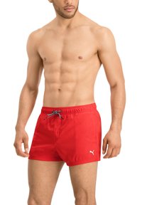 Rote Badeshorts mit Kordelzug, aus einem schnell trocknenden Material gefertigt und mit einem kleinen weißen Logo am linken Saum, designt für aktive Nutzung.
