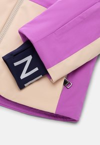 Fialová a béžová rukávová část bundy s černým vnitřním manžetovým lemem, na kterém se nachází poloviční bílý tvar písmene "N" a se stříbrným táhlem zipu.