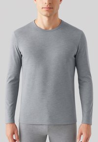Maglietta grigia a maniche lunghe in morbido tessuto, con scollatura rotonda e design aderente. Texture liscia con un sottile motivo mélange.