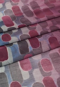 Tissu à motif de formes arrondies superposées dans des teintes de bourgogne, de gris et de bleu, avec une texture lisse et une finition douce.