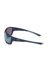 Occhiali da sole Timberland di colore blu scuro con design avvolgente e lenti oscurate, con testo del marchio e materiali ecologici stampati sulle tempie.