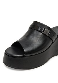 Sandalie cu platformă din piele neagră, cu vârf deschis, design elegant și o curea subțire cu un accent metalic. Textură netedă și formă rotundă.