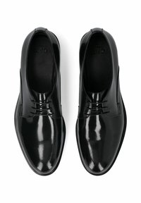 Sorte laklædersko med rundet tå, minimale snørelementer og en glat, blank overflade. Indvendigt har de en blød foring.