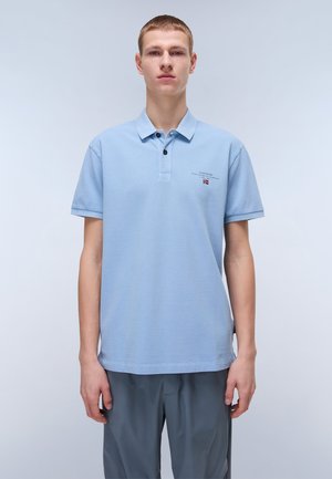 Polo shirt celeste con maniche corte, chiusura a due bottoni e piccolo logo. Il tessuto sembra strutturato e traspirante.