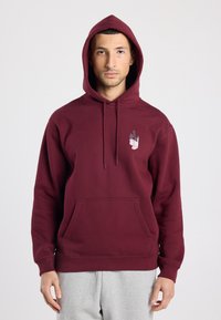 Sweat à capuche bordeaux en mélange de coton, avec une poche avant et un imprimé graphique en blanc et gris sur la poitrine gauche.