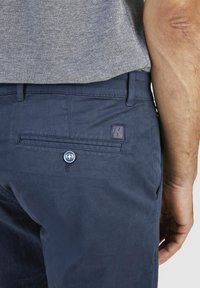 Marineblaue Baumwollhosen mit strukturierter Oberfläche, ausgestattet mit einer Gesäßtasche mit Knopf und einem dezenten Logoetikett.