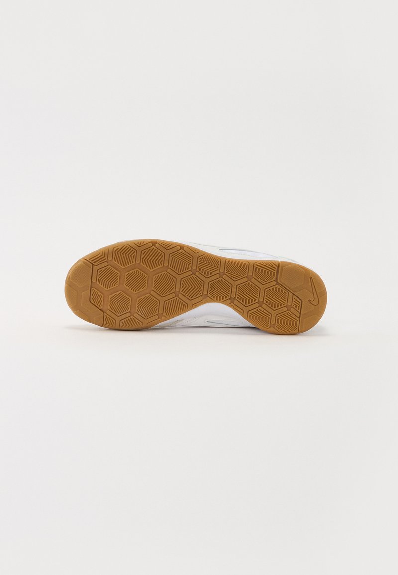 Zapatilla deportiva blanca con una suela de goma duradera. La suela presenta un patrón hexagonal que mejora la tracción y el agarre.