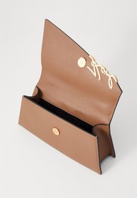 Brun lærpung med gullmetall-detaljer og trykklås. Har en logo detaljer og et åpent indre for oppbevaring.