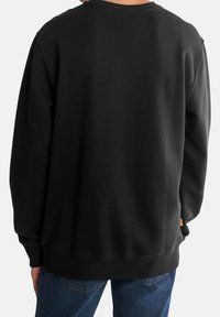 Zwarte sweatshirt met ribgebreide mouwen en zoom, oversized pasvorm en een klein logolabel aan de onderkant. Zacht materiaal met een gladde textuur.
