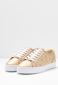 Sneakers dorati con superficie testurizzata, dotati di lacci bianchi, logo in rilievo e accenti a motivo puntinato sui lati. Suole in gomma bianche.