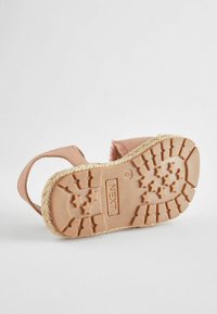 Rosa Stoffsandale mit einer strukturierten, tanfarbenen Gummisohle, die Sternmuster aufweist, und einem Espadrille-artigen Jutekante. Zwei verstellbare Riemen.