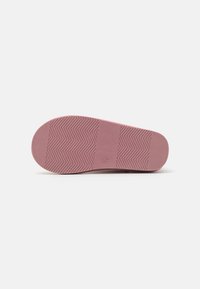 Sole di scarpe in gomma rosa con motivo a spina di pesce, superficie testurizzata e zona della punta arrotondata, progettata per trazione e comfort.