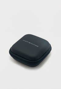 Συμπαγής μαύρη θήκη με φερμουάρ, με το λογότυπο Tommy Hilfiger στο κέντρο της κορυφής, σε απλό ανοιχτό φόντο.