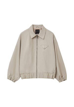 Veste légère beige avec zip, coupe oversize, poignets et ourlet élastiqués, dotée d'une petite poche sur la poitrine avec un rabat pointu.