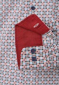 Herrenhemdkragen mit einem blauen, roten und schwarzen geometrischen Muster auf leichtem Stoff; kontrastierender roter Innenkragen mit marineblauen Knöpfen.
