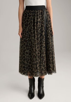Gonna in tulle con stampa leopardata, dotata di una vita elastica nera e nastri laterali. Indossata con stivaletti neri aderenti, che mettono in mostra un design a strati.