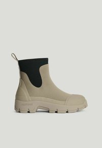 Beige ankellang regnstøvle med sort elastisk sidepanel, tyk robust sål, trækflig ved hælen og struktureret tåhætte.
