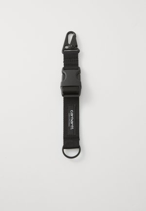 Black fabric strap featuring a plastic clip at one end and a metal ring at the opposite end. Includes a logo patch on the strap.