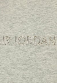 Hellgrauer Sweatshirt mit gesticktem "AIR JORDAN"-Schriftzug in einem etwas dunkleren Grauton. Der Stoff hat eine glatte, leicht strukturierte Oberfläche.