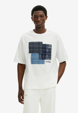 T-shirt bianco in cotone con stampa geometrica in motivi blu navy, blu scuro e blu chiaro. Maniche corte e design a vestibilità rilassata.