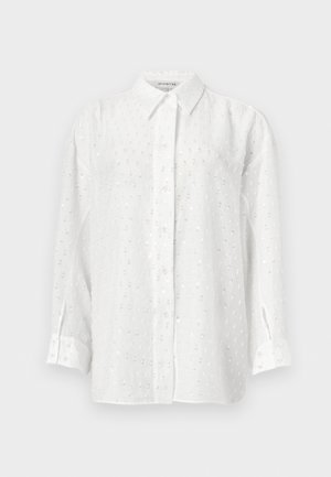 Bílé košile s dlouhým rukávem na knoflíky s jemným vzorem z teček s flitry a klasickým límečkem na jednobarevném pozadí.
