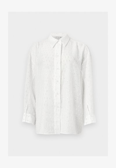 Cămașă albă cu mâneci lungi, cu nasturi, cu un model subtil punctat din paiete și guler clasic pe fundal simplu.