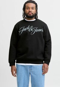 Must be musta suur aqua sinise "Jack & Jones" logo. Omab soonikuid varrukaid ja äärt. Kanda valge kihilise särk ja sinised teksad.