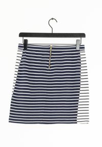 Marineblauwe en witte gestreepte rok met een voorkeursrits, gemaakt van zachte stof. Heeft verschillende streepjespatronen aan de zijkanten. Hangt aan een zwarte haak.