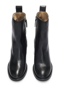 Botas de cuero negro hasta el tobillo con textura suave, puntera redonda y cremalleras laterales. Presenta una asa en la parte trasera y una suela de goma baja.