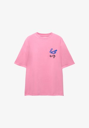 T-shirt in cotone rosa con vestibilità rilassata. Presenta una grafica di un'onda blu e testo nero sul lato sinistro del petto. Maniche corte e colletto a girocollo.