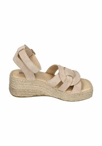 Beige suede wedge sandals with cross-strap design, ankle strap, and woven jute sole. Features a smooth texture and minimal hardware.