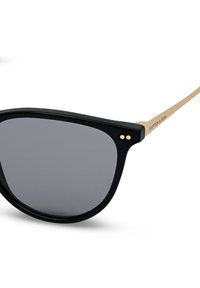 Zonnebril met zwart montuur, donkere glazen en dunne beige pootjes, met "KAPTEN & SON" branding op de poot.