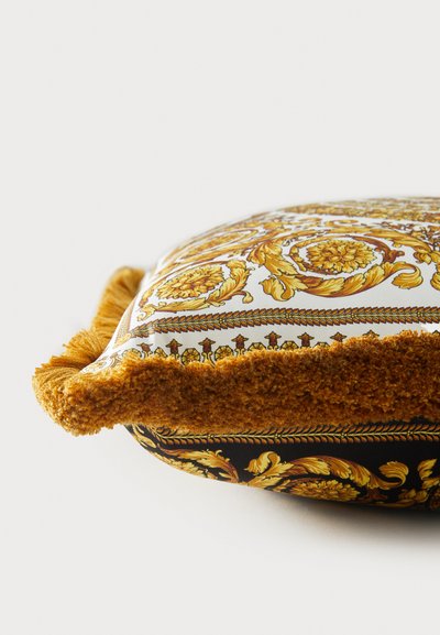 Ορθογώνιο μαξιλάρι με περίτεχνο χρυσό ανθικό σχέδιο σε λευκό ύφασμα, τελείωμα μουστάρδας με φούντες και μαύρη βάση με αντίθετο σχέδιο.