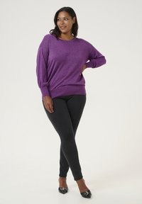 Purple glitter long-sleeve sweater with a relaxed fit, paired with black skinny jeans and pointed black heels. Smooth texture and simple design.