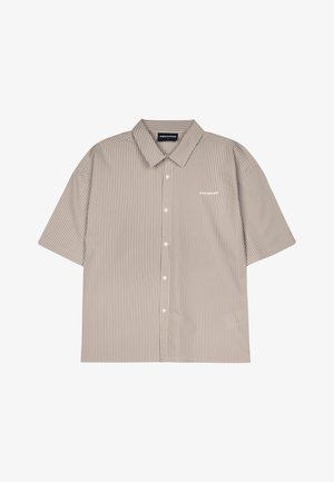 Kratkoročna, srajca s kragnico v bež barvi z belimi navpičnimi črtami. Ima gumbe spredaj in majhen bel znak na prsih.