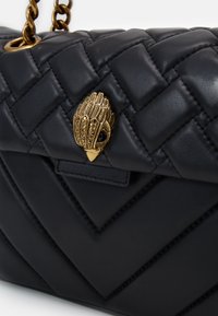 Borsa a tracolla in pelle nera con motivo a chevron trapuntato, dotata di una chiusura a forma di foglia color oro con decorazioni e una tracolla a catena.