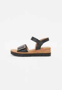Black wedge sandals with a smooth leather upper, adjustable strap and a contrasting cork sole. Features a metallic accent on the front.