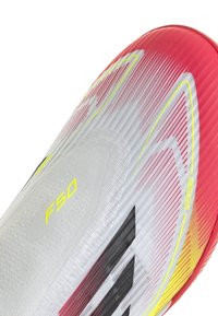 Fußballschuh mit einem Farbverlauf-Design in Rot, Weiß und Gelb. Strukturierte Oberfläche mit schwarzen Streifen und "F50"-Aufschrift.