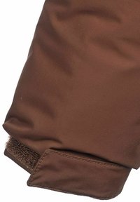 Brun jackärm i slät tyg. Velcro-stängning i änden med en subtil struktur. Sömmar längs kanten för hållbarhet.