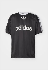 Fekete, rövid ujjú póló fehér "adidas" logóval és három csíkkal mindkét válltömjén. Simább, könnyű anyagból készült, kerek nyakkal.