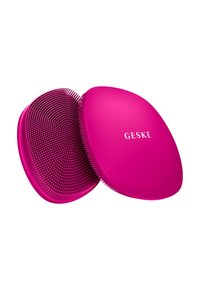 Hellpinkes ovales Gesichtreinigungsbürstchen mit weichen Silikonborsten, eine Seite zeigt eine strukturierte Oberfläche, die andere mit dem eingeprägten Markennamen "GESKE".