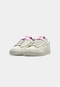 Hvite lær sneakers med lilla og rosa detaljer, rund tå, teksturert gummisåle og perforerte detaljer på sidene.