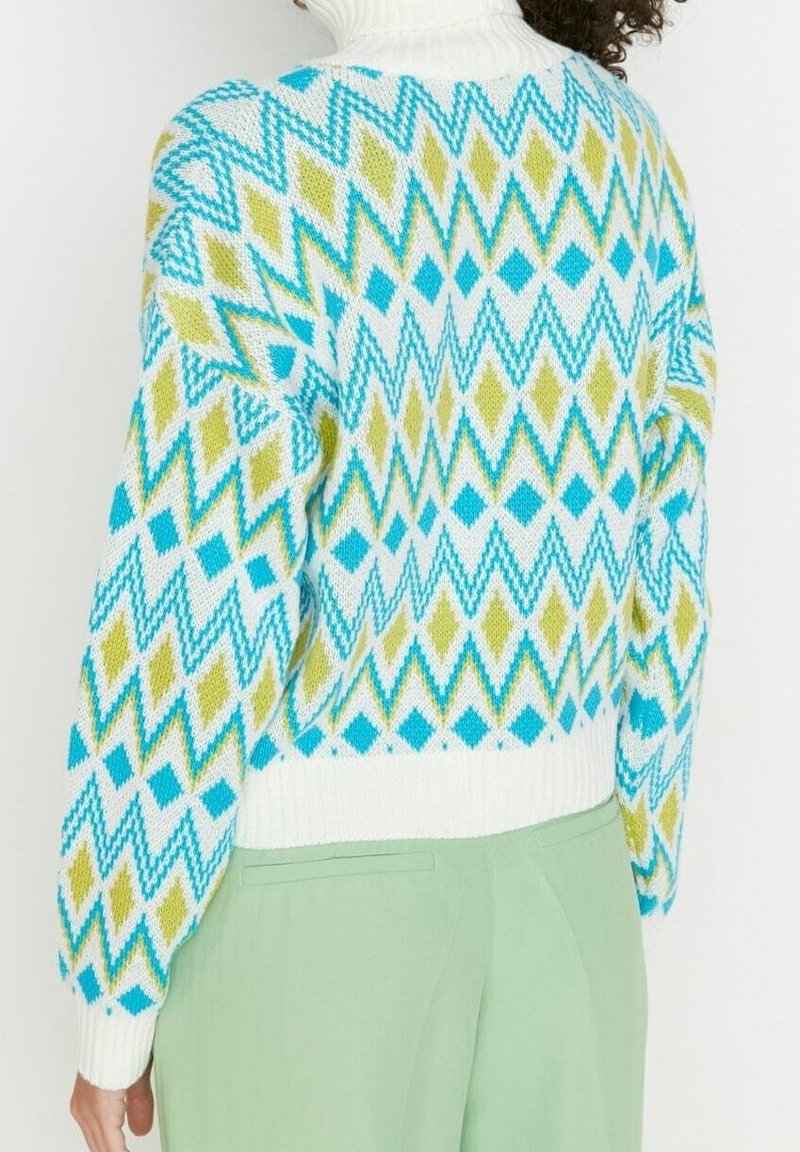 Gebreide trui met een geometrisch patroon in blauw, teal en limoengroen op een witte achtergrond; hoge hals en geribde manchetten.