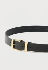 Cinturón de cuero negro con hebilla metálica dorada, con textura lisa, forma rectangular y varios agujeros para ajustar la talla.