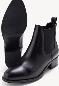 Bottines en cuir noir avec panneaux élastiques sur les côtés, bout rond et petit talon carré. Semelle en caoutchouc texturée. Fini lisse.