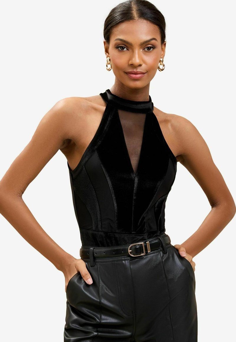Mustast halter kaelusega bodysuit, millel on läbipaistev võrkpaneel, valmistatud pehmest sametist. Omab vormivaadiseid ja õhukaid vertikaalseid õmblusi, et rõhutada figuuri.