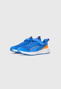 Baskets de sport bleues avec tige en mesh, semelle blanche et accents oranges. Dotées d'une sangle réglable et d'une surface texturée pour une meilleure adhérence.